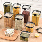 Set of clear food storage containers with black lids on a kitchen counter.