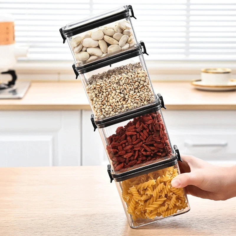 Stack of clear containers with black lids filled with various foods on a kitchen counter.